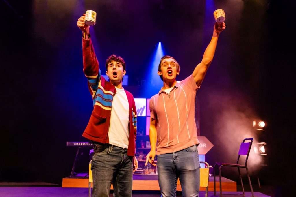 Hunter and Jeff raise their mugs in the air in a cheers-ing motion