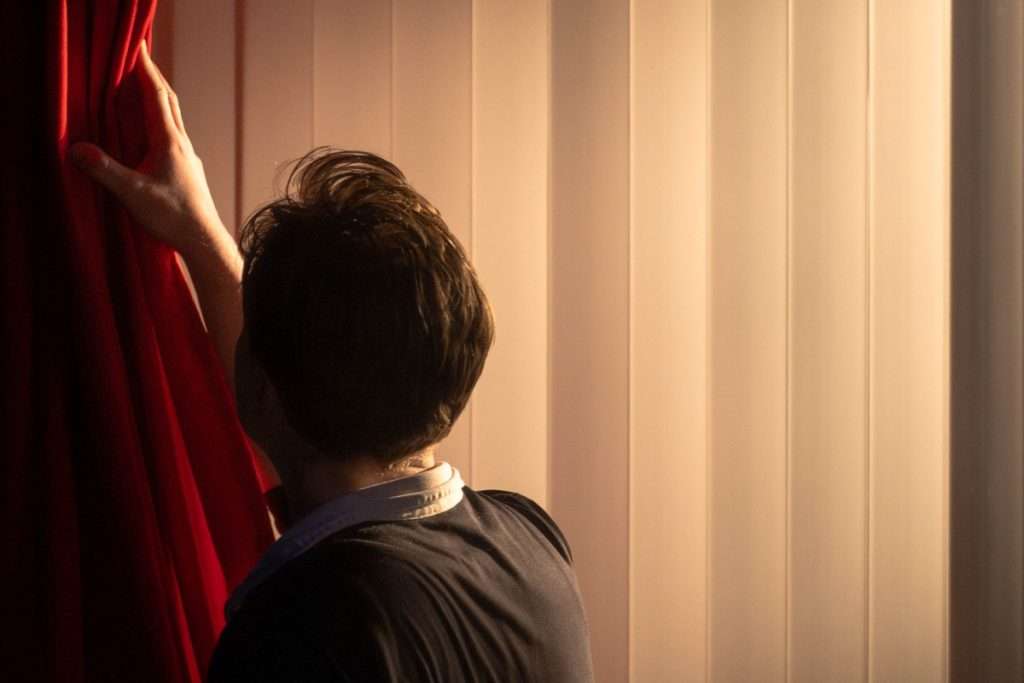 Oliver Maynard pushes a red curtain back